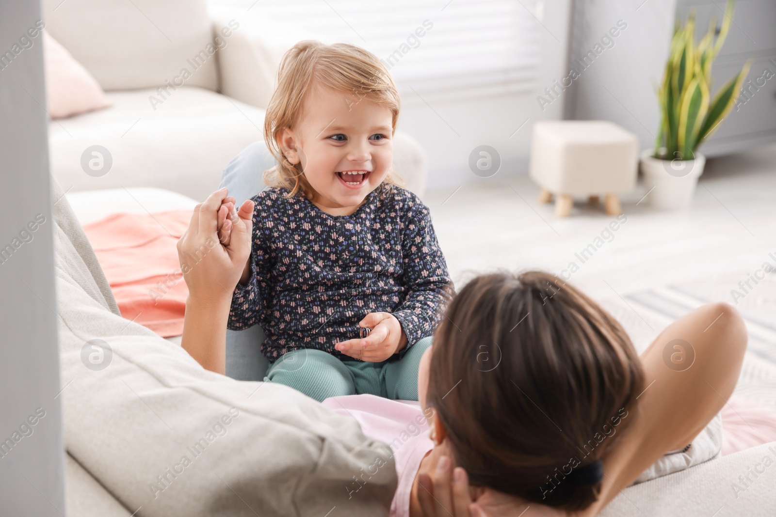 Photo of Mother with her cute little daughter on sofa at home