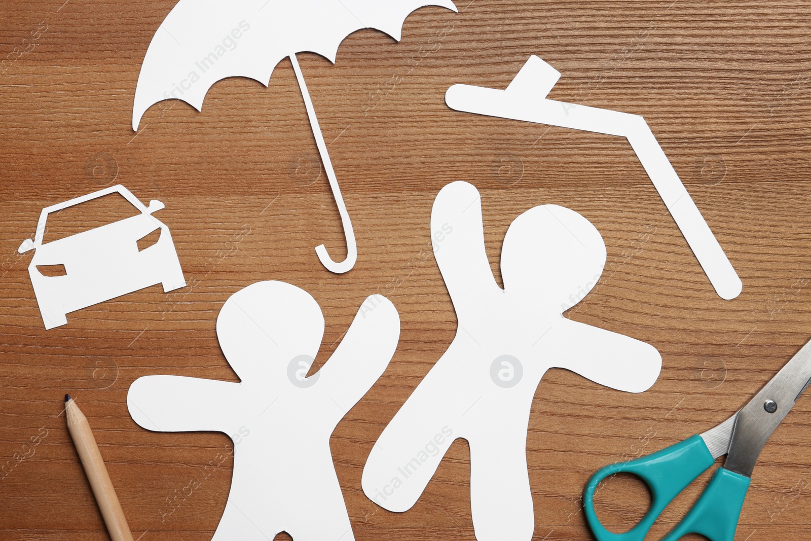 Photo of Flat lay composition with paper silhouettes of people with umbrella and scissors on wooden background. Life insurance concept