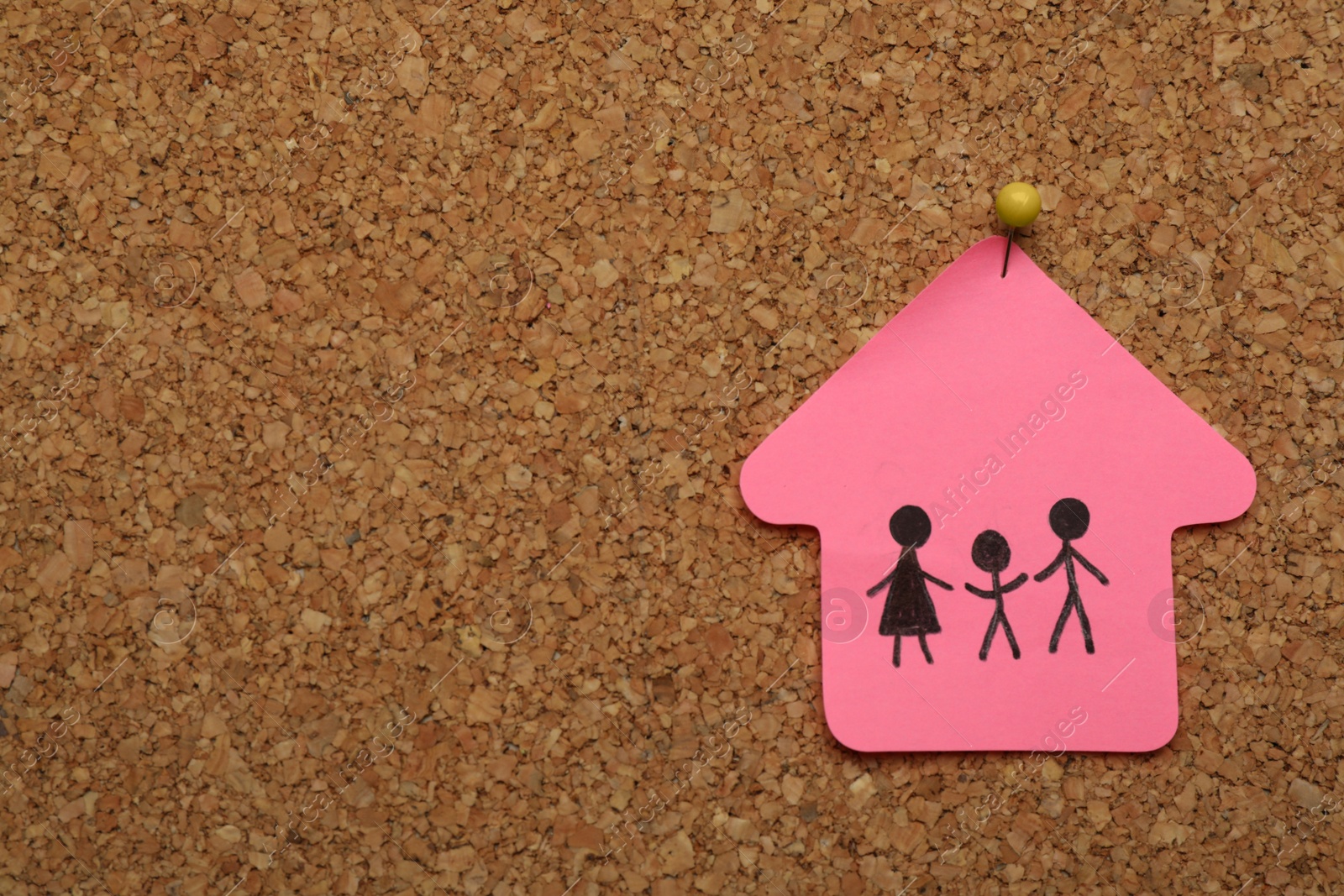 Photo of House shaped note with drawing of family pinned to cork board, space for text. Child adoption concept