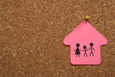 Photo of House shaped note with drawing of family pinned to cork board, space for text. Child adoption concept