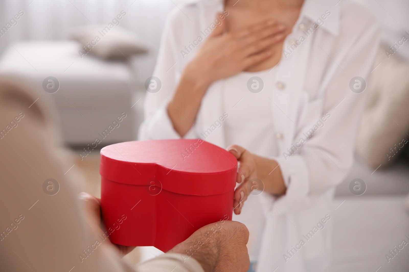 Photo of Man presenting gift to his beloved woman at home, closeup. Valentine's day celebration