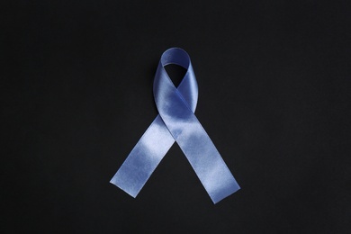 Purple awareness ribbon on black background, top view