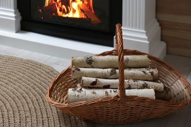 Firewood in wicker basket near fireplace indoors