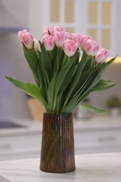 Beautiful bouquet of fresh pink tulips on table in kitchen