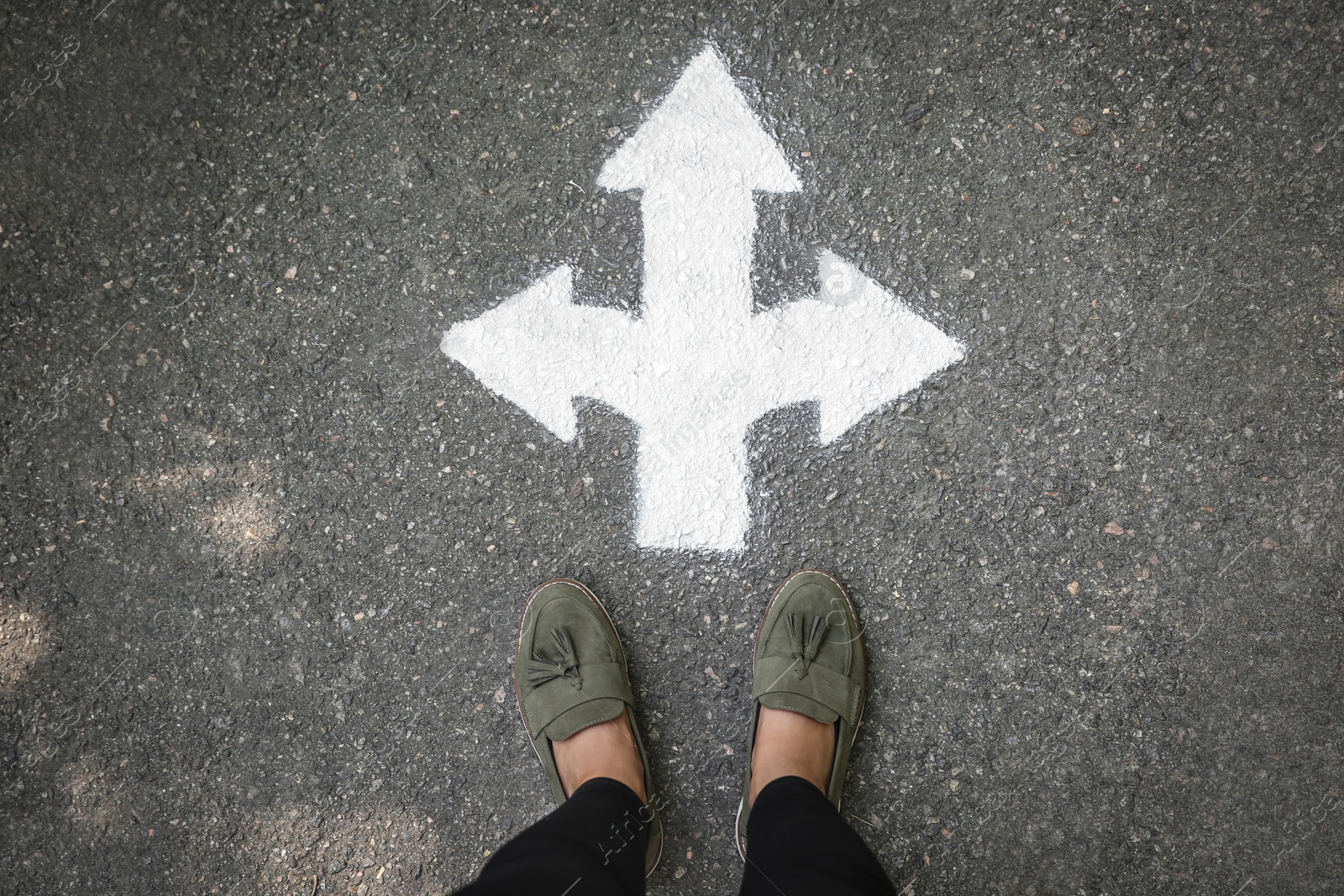 Photo of Woman standing near arrow on asphalt, top view