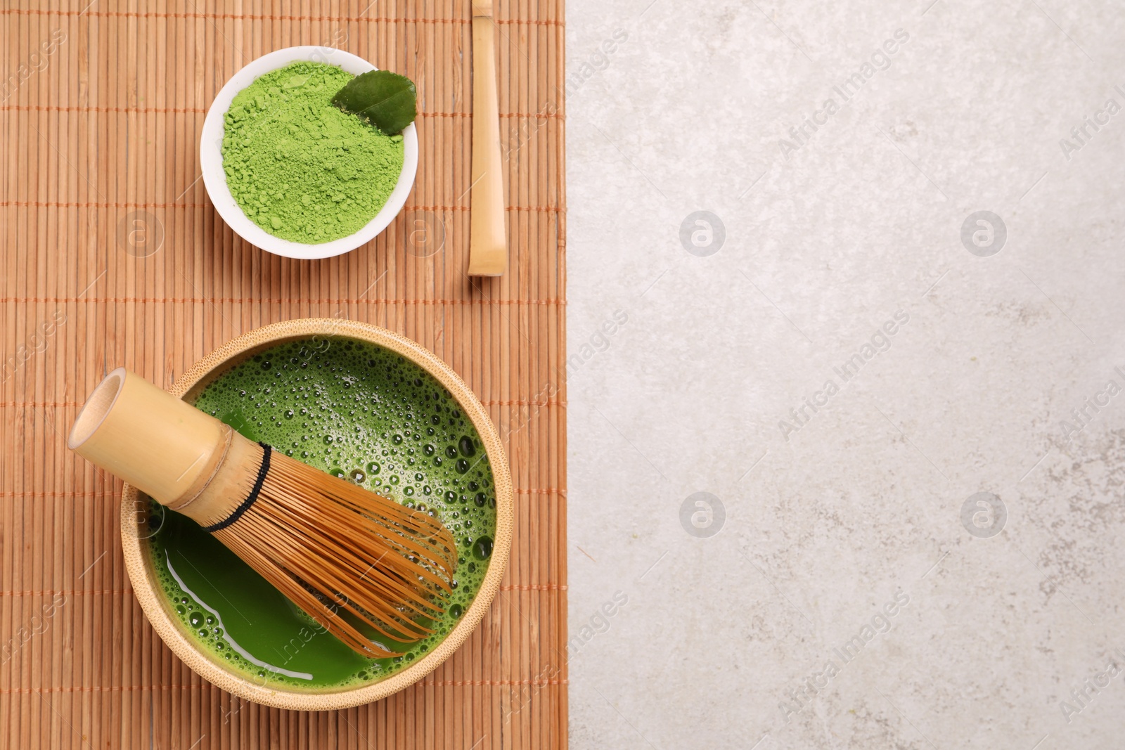 Photo of Bowl of fresh matcha tea with bamboo whisk and powder on light table, top view. Space for text