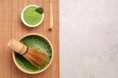 Photo of Bowl of fresh matcha tea with bamboo whisk and powder on light table, top view. Space for text