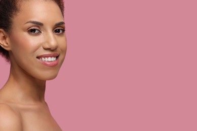 Photo of Beautiful young woman with glamorous makeup on pink background, closeup. Space for text