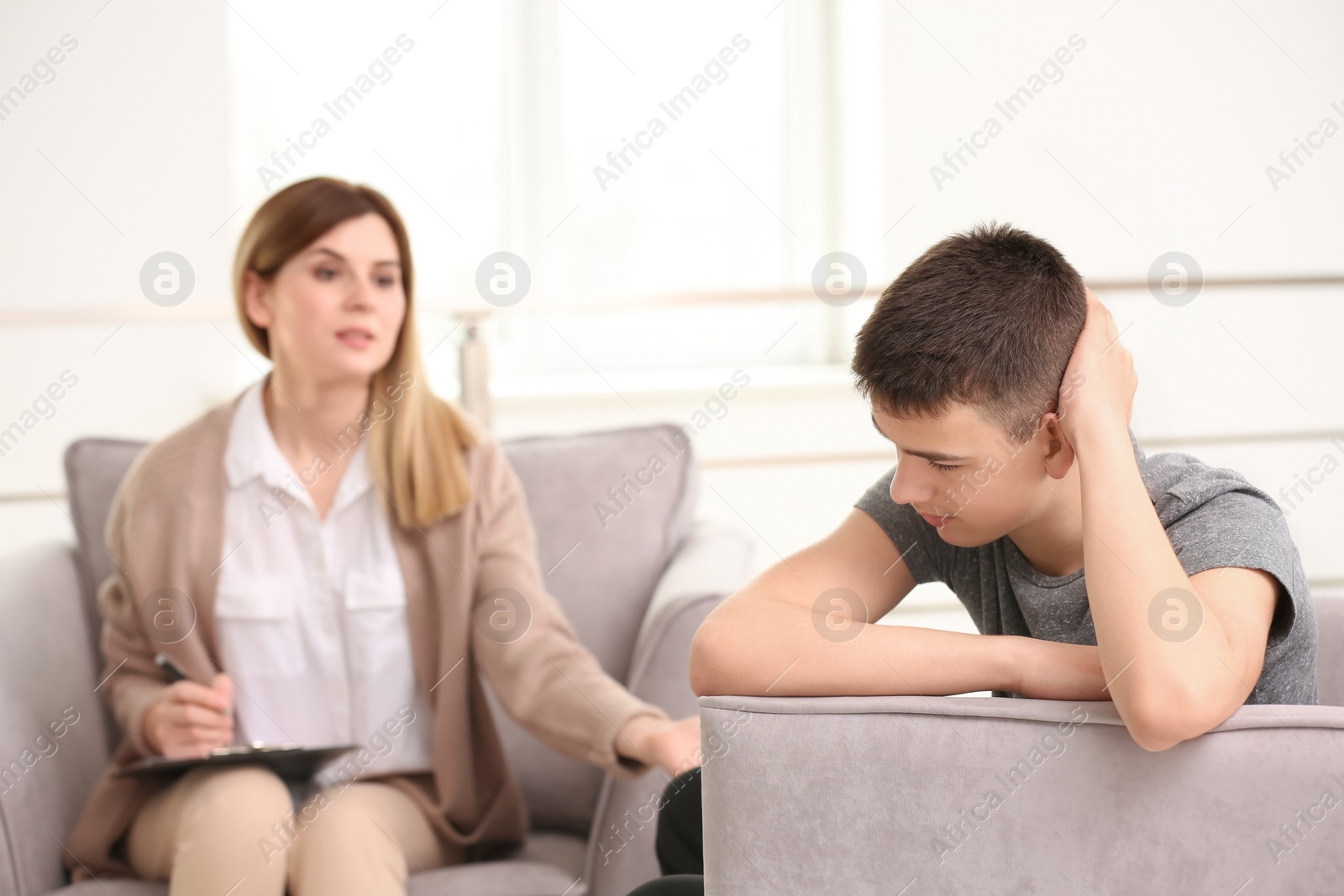 Photo of Young female psychologist working with teenage boy in office