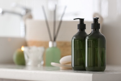 Green soap dispensers on countertop near sink in bathroom. Space for text