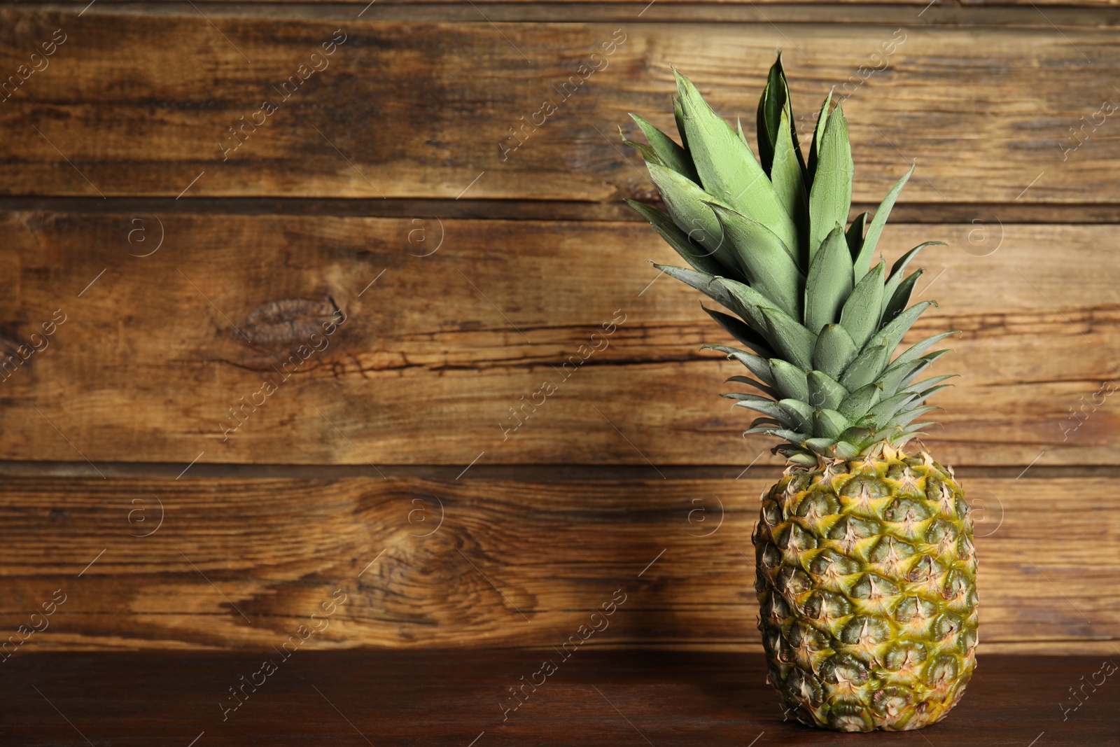 Photo of Fresh ripe juicy pineapple on wooden table. Space for text