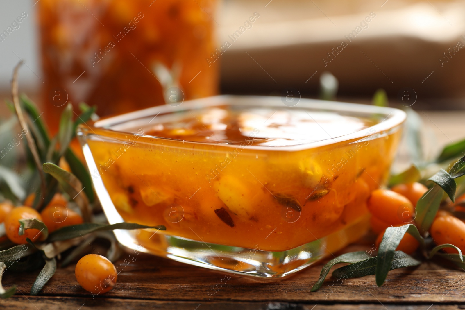 Photo of Delicious sea buckthorn jam and fresh berries on wooden table, closeup