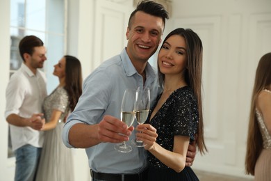 Lovely young couple with glasses of champagne at dancing party