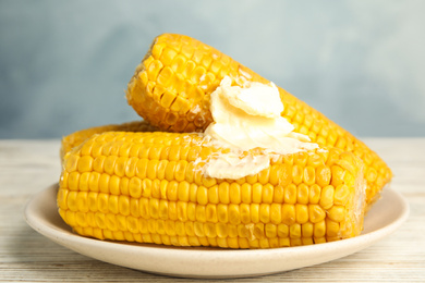 Photo of Delicious boiled corn with butter on white wooden table