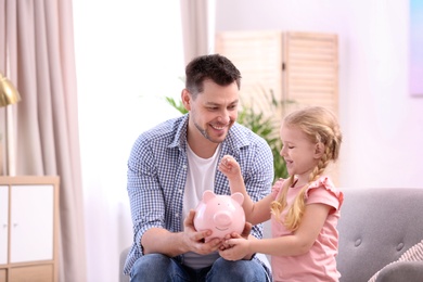 Photo of Family with piggy bank and money at home