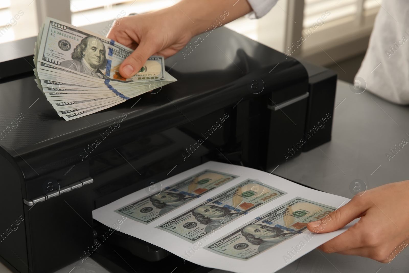 Photo of Counterfeiter printing dollar banknotes at grey table indoors, closeup. Fake money concept