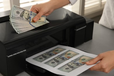 Photo of Counterfeiter printing dollar banknotes at grey table indoors, closeup. Fake money concept