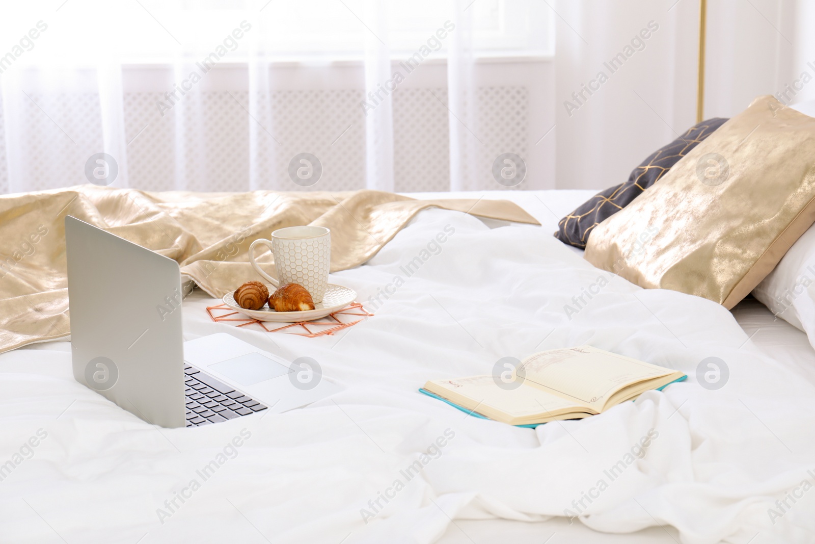 Photo of Laptop and breakfast on bed in stylish room interior