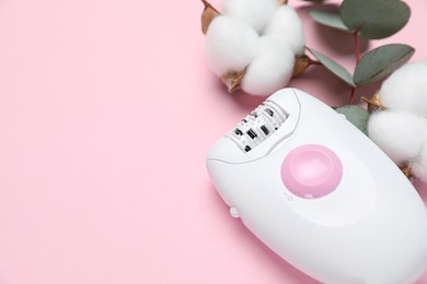 Modern epilator, fluffy cotton flowers and eucalyptus branch on pink background, closeup. Space for text
