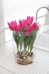 Bouquet of beautiful tulips with bulbs on countertop in kitchen