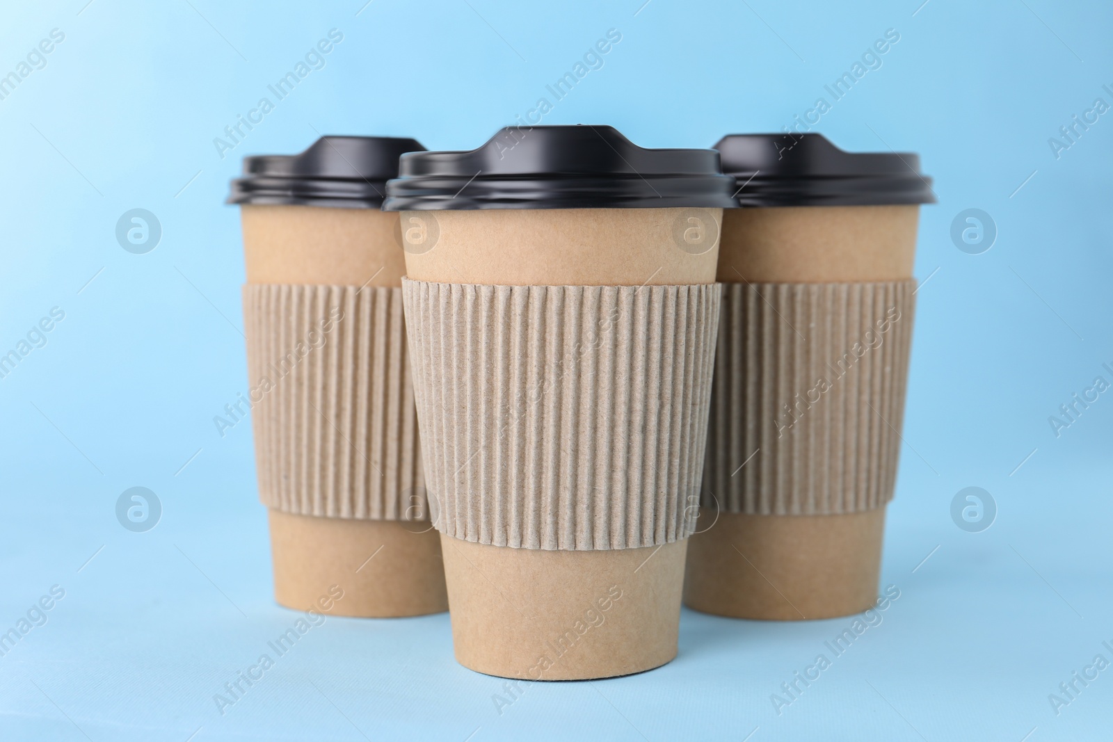 Photo of Paper cups with black lids on light blue background. Coffee to go