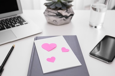 Photo of Greeting card with hearts at workplace. Valentine's Day celebration