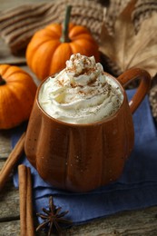 Photo of Mug of pumpkin spice latte with whipped cream and ingredients on wooden table