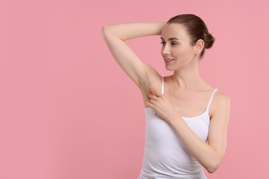 Beautiful woman showing armpit with smooth clean skin on pink background, space for text