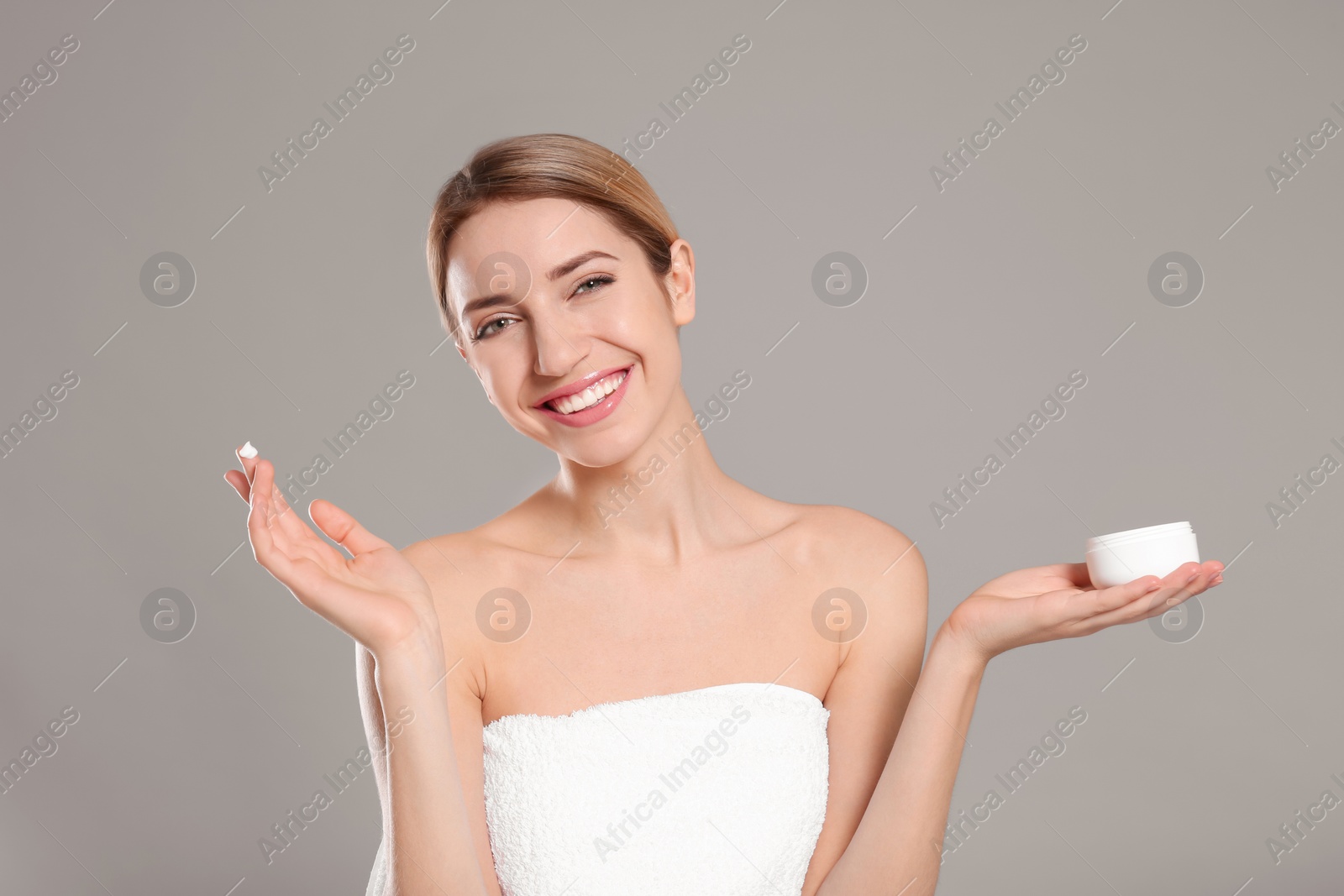 Photo of Young woman with jar of body cream on color background