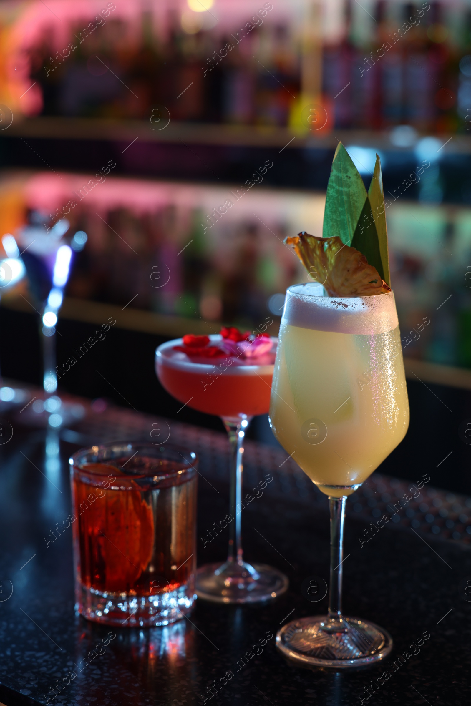 Photo of Different fresh alcoholic cocktails on counter in bar