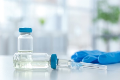 Photo of Vials and syringe with medicine on blurred background. Vaccination concept