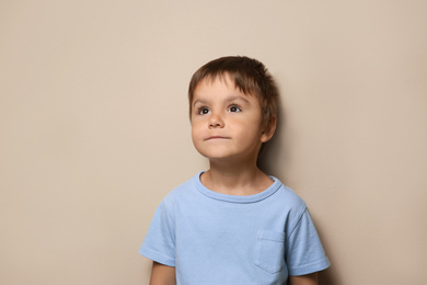 Portrait of cute little boy on beige background