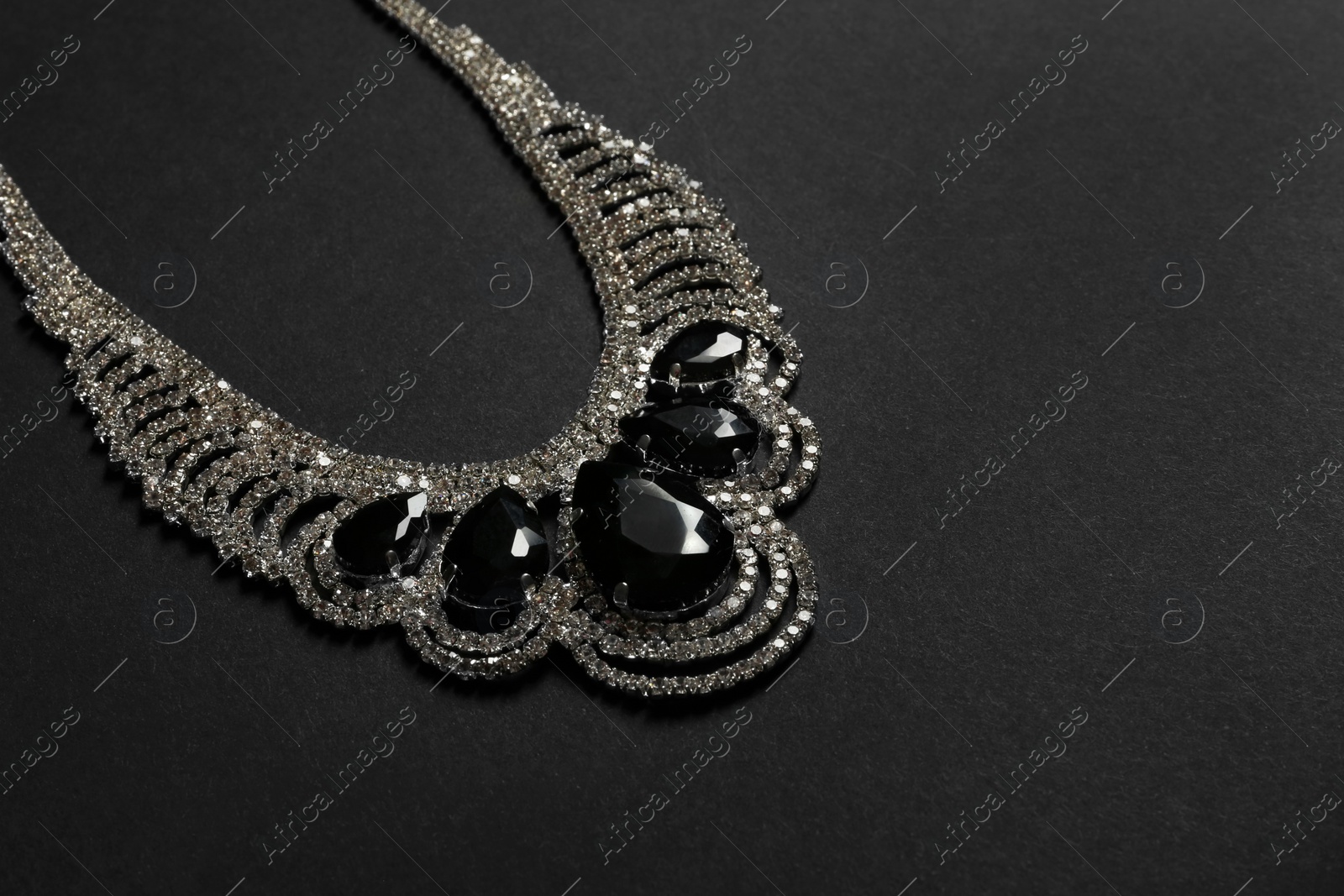 Photo of Stylish necklace with gemstones on black background, space for text. Luxury jewelry