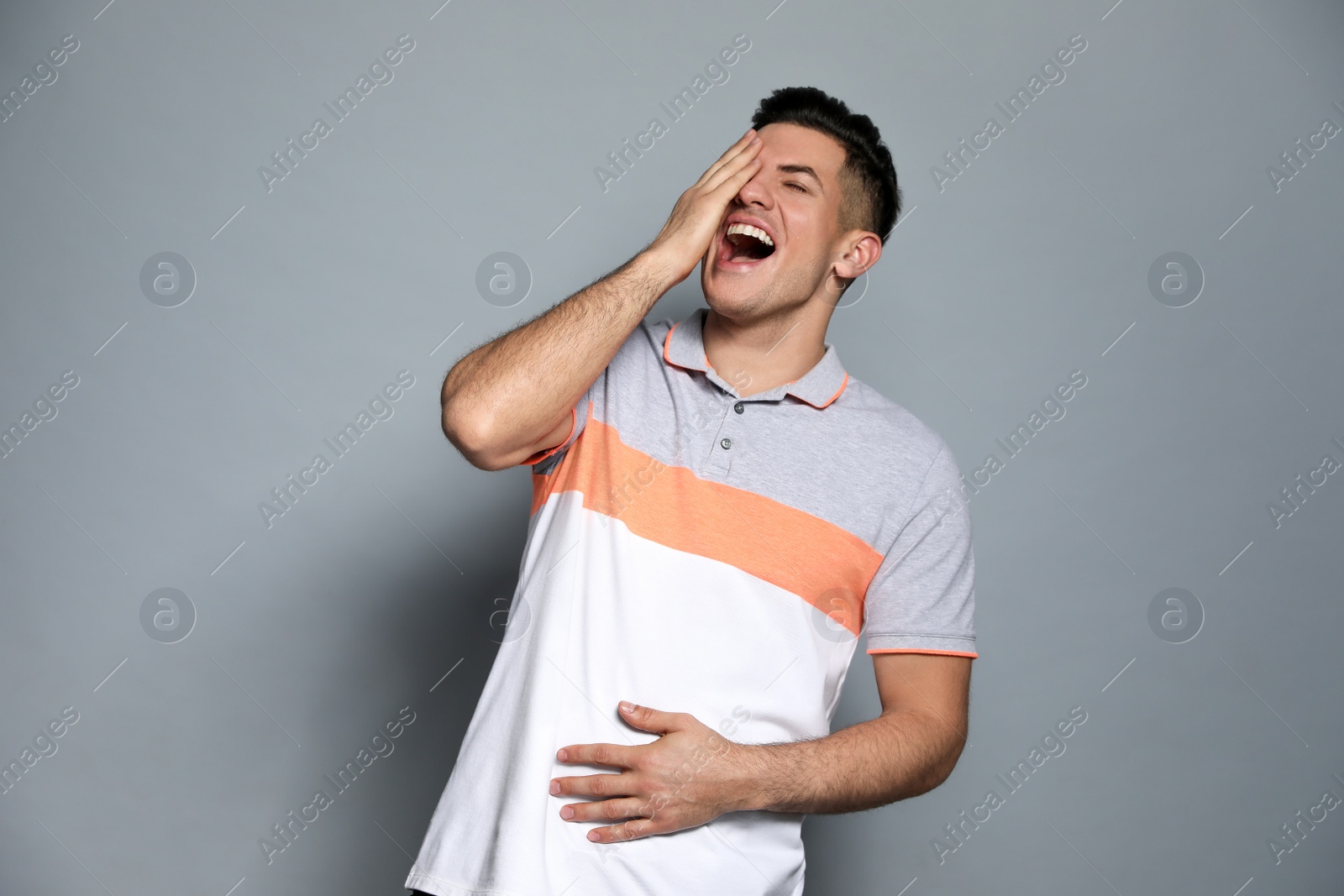 Photo of Handsome man laughing on grey background. Funny joke