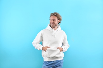 Portrait of man in hoodie sweater on color background. Space for design