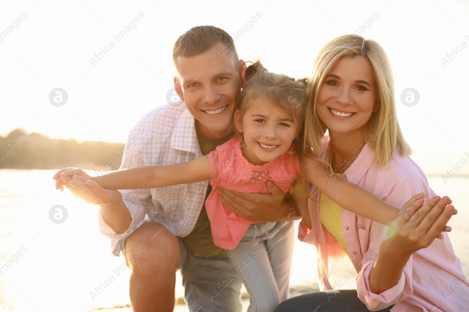 Photo of Happy parents with their child on beach. Spending time in nature