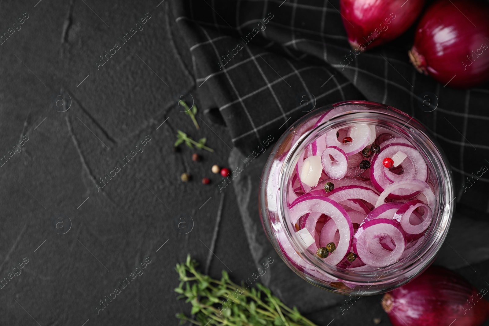 Photo of Flat lay composition with jar of tasty pickled onions on black table, space for text