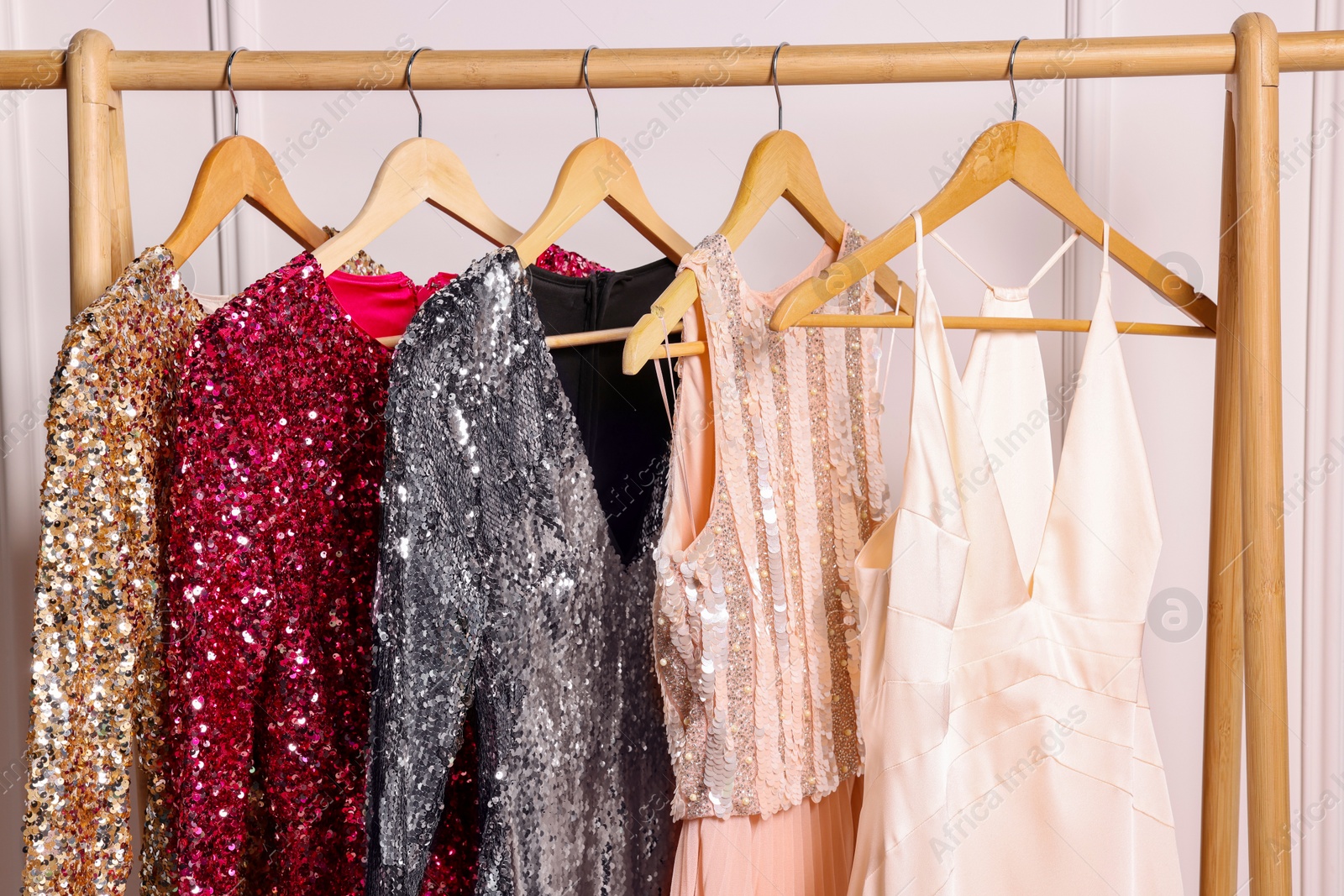 Photo of Rack with collection of stylish dresses in room. Preparing for party