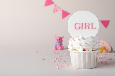 Photo of Beautifully decorated baby shower cupcake with cream and girl topper on light background. Space for text