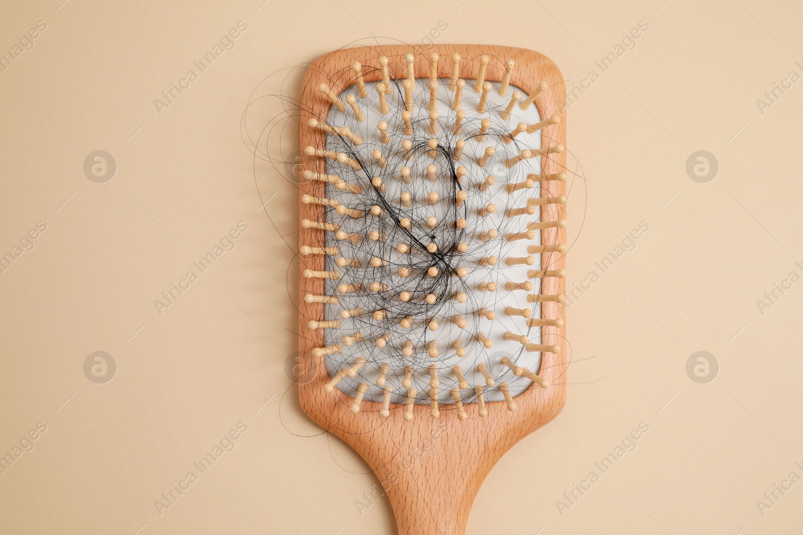 Photo of Wooden brush with lost hair on beige background, top view