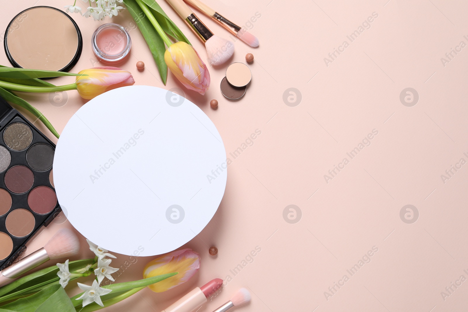 Photo of Flat lay composition with different makeup products, blank card and beautiful tulips on beige background, space for text