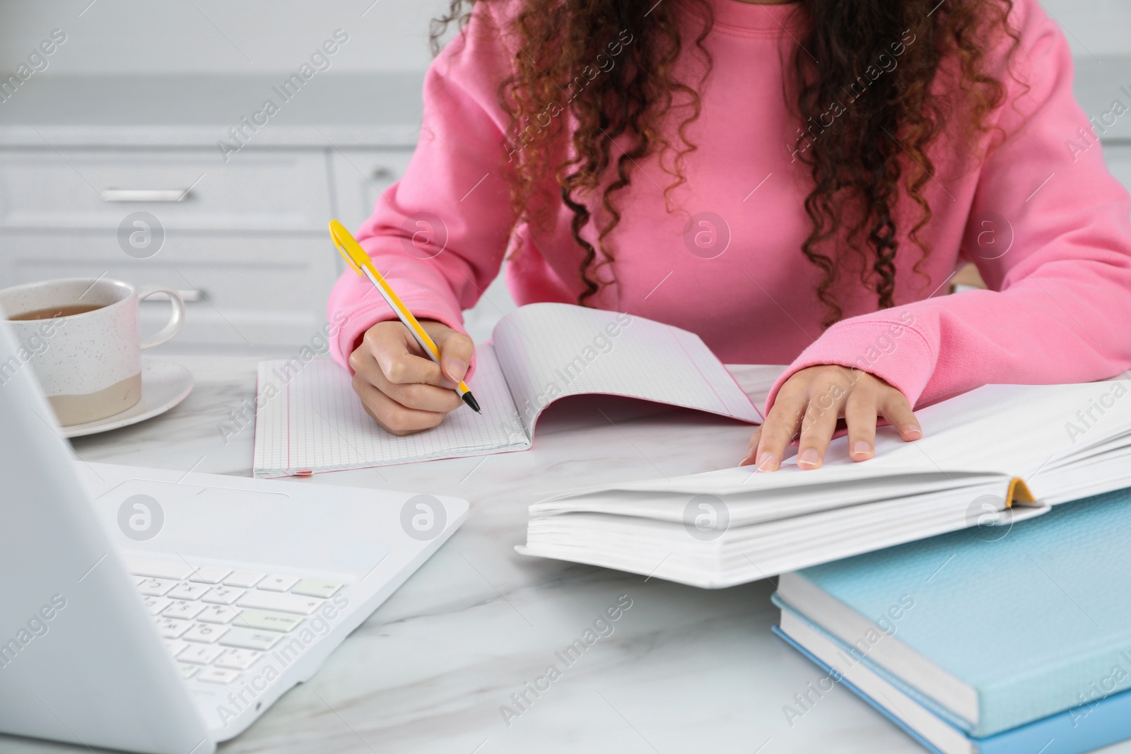 Photo of African American woman with modern laptop studying in kitchen, closeup. Distance learning