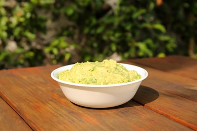 Delicious guacamole made of avocados on wooden table outdoors