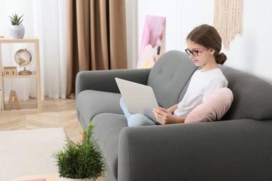Girl with laptop on sofa at home