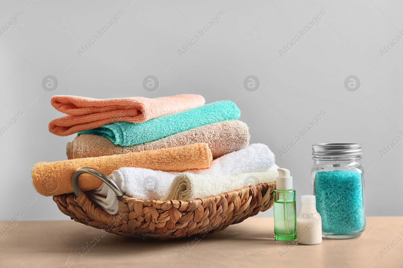 Photo of Basket with clean towels, cream and sea salt on table