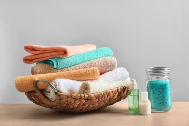 Photo of Basket with clean towels, cream and sea salt on table