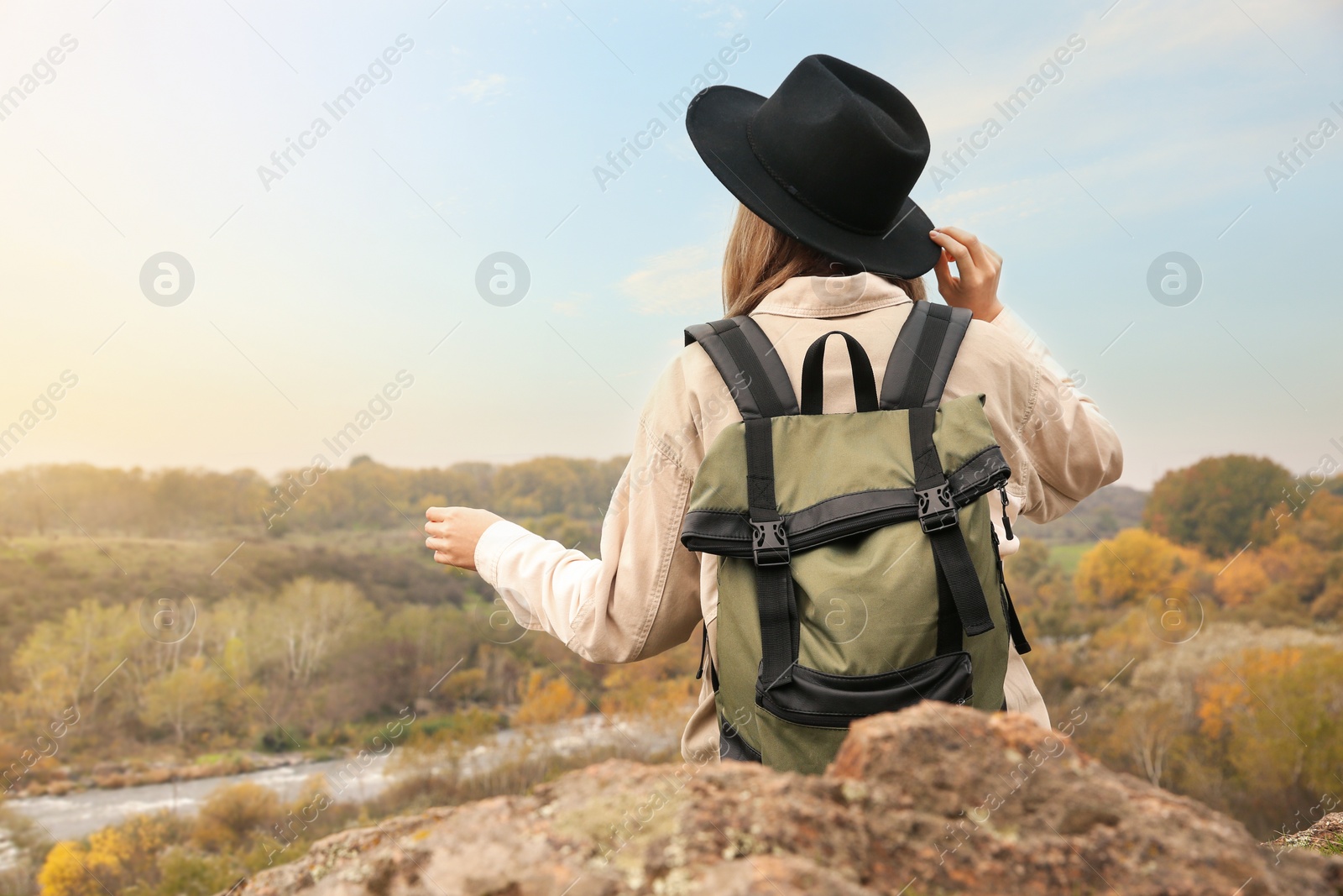 Photo of Traveler with backpack enjoying beautiful view near mountain river. Autumn vacation