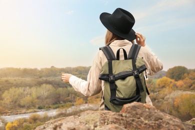 Traveler with backpack enjoying beautiful view near mountain river. Autumn vacation