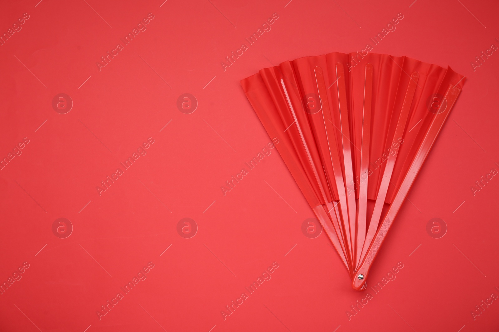 Photo of Bright color hand fan on red background, top view. Space for text