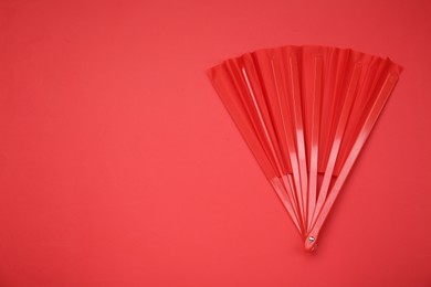 Photo of Bright color hand fan on red background, top view. Space for text